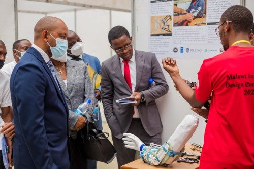 Student explaining prosthetic arm to judges at 2022 Malawi Design Competition